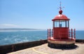 Red lighthouse lamp room on blue sky and sea background in Nazare, Portugal