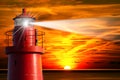 Red Lighthouse with Light Beam at Sunset Royalty Free Stock Photo