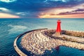 Red lighthouse on rocky harbor at sunset Royalty Free Stock Photo