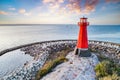 Red lighthouse on rocky harbor at sunset Royalty Free Stock Photo