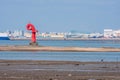 Red lighthouse on sandbar during low tide