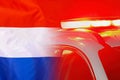 Red lights on top of Netherlands police car on the background of the Netherlands flag