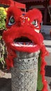 A red lion dance head custom placed on a stone pillar.