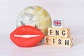 Red lip beside the cube english alphabets and vintage globe background, English learning concept.