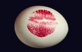 Red lip imprint on easter egg on black background. Print of red lips on white egg. Egg hunt. Royalty Free Stock Photo