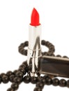 Red lipstick and black bead over white background