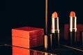 Red lipstick in black golden tube and gift jewelry box on black background with mirror reflection