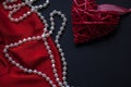 Red heart and lipstick, on a black background, a string of white pearls and a silk handkerchief Royalty Free Stock Photo