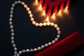 Red heart and lipstick, on a black background, a string of white pearls and a silk handkerchief Royalty Free Stock Photo