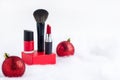 Red lipstick, nail polish, brush on podium on background of snow