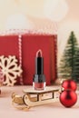 Red lipstick on a wooden sled on a New Year's background. Stylish Christmas lipstick advertisement.