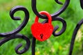 Red lock in the shape of a heart on a black fence, a symbol of love Royalty Free Stock Photo