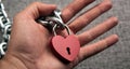 Red locked heart shaped padlock with steel chain in the male palm