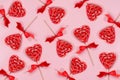 Red lollipops hearts with silk bow patten on pastel pink as festive valentine`s day background.