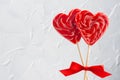 Red lollipops hearts with silk bow on white light backdrop as festive valentines day background. Royalty Free Stock Photo