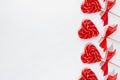 Red lollipops hearts with silk bow on white wood board as festive valentines day background, border, copy space.