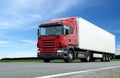 Red lorry with white trailer over blue sky