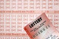 Red lottery ticket lies on pink gambling sheets with numbers for marking to play lottery. Lottery playing concept or gambling Royalty Free Stock Photo