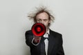 Red loudspeaker in hand of crazy businessman on white background