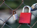 Red love lock attached to wire fence next to a rusty lock Royalty Free Stock Photo