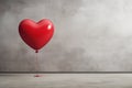 Red love shaped balloon on a gray wall background