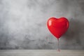 Red love shaped balloon on a gray wall background