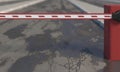 Red lowered road barrier close-up on a blurred background of wet cracked asphalt road with pits and puddles. 3D rendering Royalty Free Stock Photo