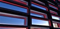 Red luminous window frames as a day decor of the contemporary apartment building.Black brick tile facade finishing. Reflection of