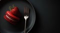 Red macaron and strawberry on black plate with silver fork, dark background Royalty Free Stock Photo