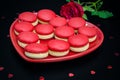 Red macaroon on black background with red roses heart shaped plate