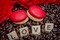 Red macaroon on rosted coffee beans background with red flowers and letters LOVE