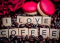 Red macaroon on rosted coffee beans background with red flowers and letters I LOVE Coffee