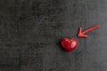 Red magnet arrow pointing to shiny ceramic red heart shape on cement chalkboard wall, minimal concept for Happy Valentine`s day