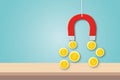 Red magnet attracting many coin on table and pastel blue background as metaphor of concept attract investment.