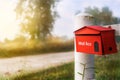 Red mailbox on white wooden fence in morning sunshine light, selective focus Royalty Free Stock Photo