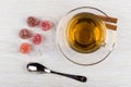 Red marmalade, tea on saucer, cinnamon and teaspoon on table