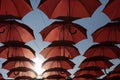 Red Marsala Umbrellas Against The Blue Sky And Sun. View From Below. Abstract Background With Red Umbrellas. Seamless Pattern Wit