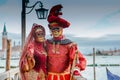 Red masked couple on the pontoon in Venice Royalty Free Stock Photo