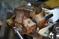 Red massive locksmith iron vise on an iron table