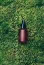Red matt glass cosmetic bottle on green background, natural moss, grass. Skin care, organic body treatment, spa concept Royalty Free Stock Photo