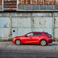 A red Mazda 3 parked in front of an old airplane hangar. Mazda 3 produced in 2013-2019. Katowice- Poland, February 15, 2015