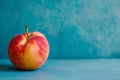 A red McIntosh apple, a seedless fruit, is on a blue table Royalty Free Stock Photo