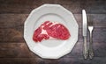 Red meat / raw steak on plate on wooden background with knife and fork Royalty Free Stock Photo