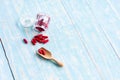 Red medicines in the glass bottles on the wooden spoon and blue table. Royalty Free Stock Photo