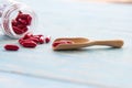 Red medicines in the glass bottles on the wooden spoon and blue table. Royalty Free Stock Photo