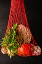 Red mesh bag with fresh vegetables on a black background. Zero waste, eco friendly or plastic free lifestyle concept Royalty Free Stock Photo