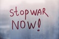 Red message call Stop war now are painted handwriting on blue window with raindrops