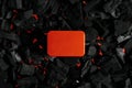 Red metal box on charcoal back. Copy space in a rectangle on a background of hot coals