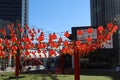 Red metal chairs with red Chinese lanterns hanging from the sky surrounded by red brick office buildings and shops