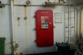Red metal door with stickers is closing the entrance to safety locker on the container vessel.